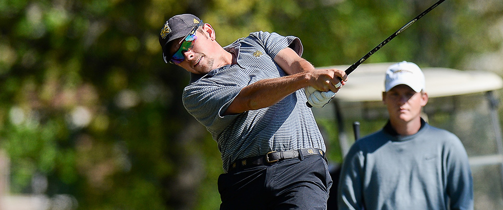“Wyatt Larkin swings golf club at tournament, coach watches, green course backdrop.” 